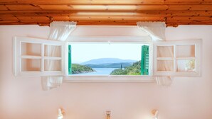 Una habitación con ventana que da a un lago y montañas.