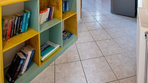 Une cuisine équipée d’un réfrigérateur, d’une table à manger avec des chaises et d’une bibliothèque remplie de livres.
