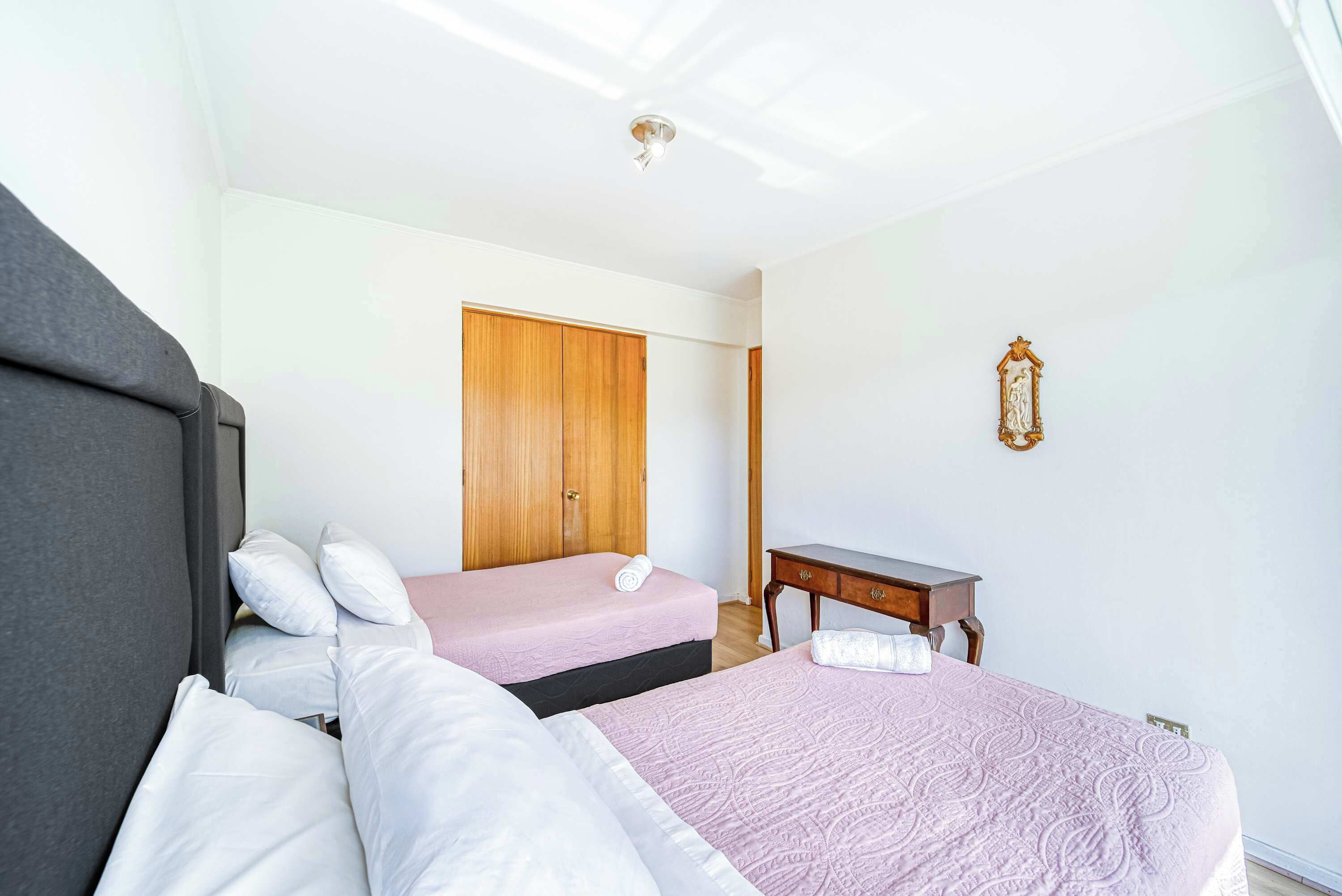 Een hotelkamer met twee bedden, een houten kast, een tafeltje en een decoratie aan de muur.