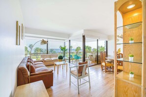 A spacious living area with a sofa, chairs, a dining table, and a balcony with a view. - Beach Paradise 4BR with view (Viña del Mar)