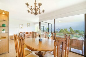 A spacious dining area with a large wooden table and chairs, a chandelier, and a view of the ocean through large windows. - Beach Paradise 4BR with view (Viña del Mar)