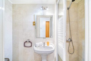A bathroom with a white sink, a mirror, a shower, and a toilet. - Beach Paradise 4BR with view (Viña del Mar)