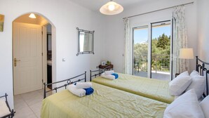 Ein Schlafzimmer mit zwei Betten, einem Balkon und Blick auf Grünflächen.