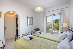 Ein Schlafzimmer mit zwei Betten, einem Balkon und Blick auf Grünflächen.