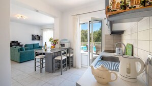 Eine moderne Küche mit Wasserkocher, Toaster und Kaffeemaschine. Es gibt einen Essbereich mit Tisch und Stühlen.