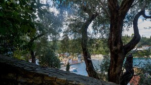 A stone wall overlooking a body of water with buildings in the background. - Aglaia Studio in Longos (Longos)
