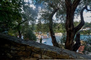 A stone wall overlooking a body of water with buildings in the background. - Aglaia Studio in Longos (Longos)