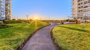 A pathway leading to a sunset view, surrounded by well-maintained grass and modern buildings. - Beach View 2D increible ubicacion (Valparaíso)