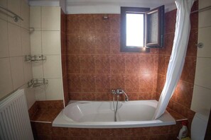 A bathroom with a bathtub, a shower, and a window. - Foula House in Magnisia (Magnisia)