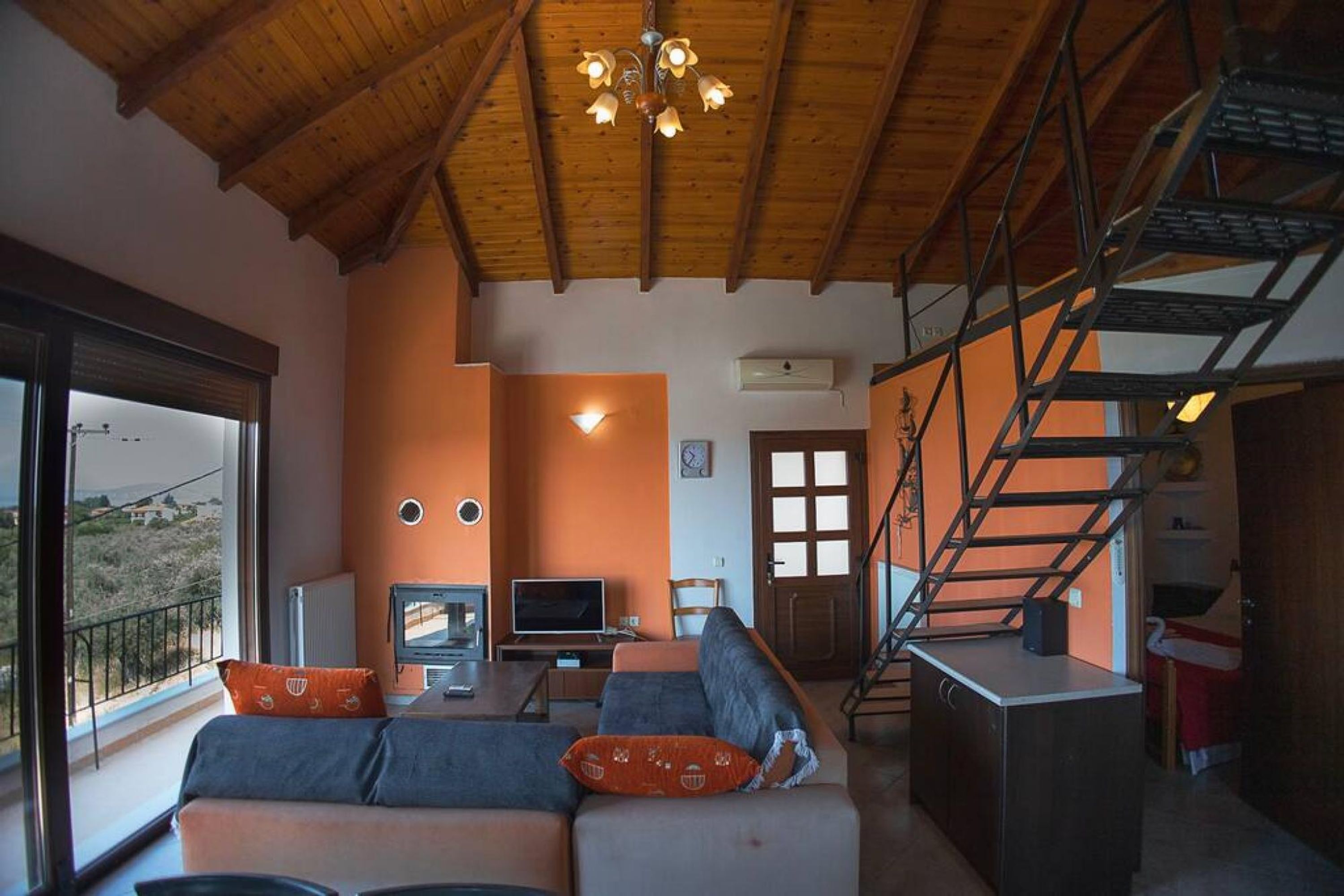 A modern living room with a sofa, television, and a staircase.