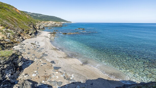 A coastal beach with clear water, rocky shore, and a hilly landscape in the background. - Nerissa Cottage - Skopelos Glossa (Glossa)