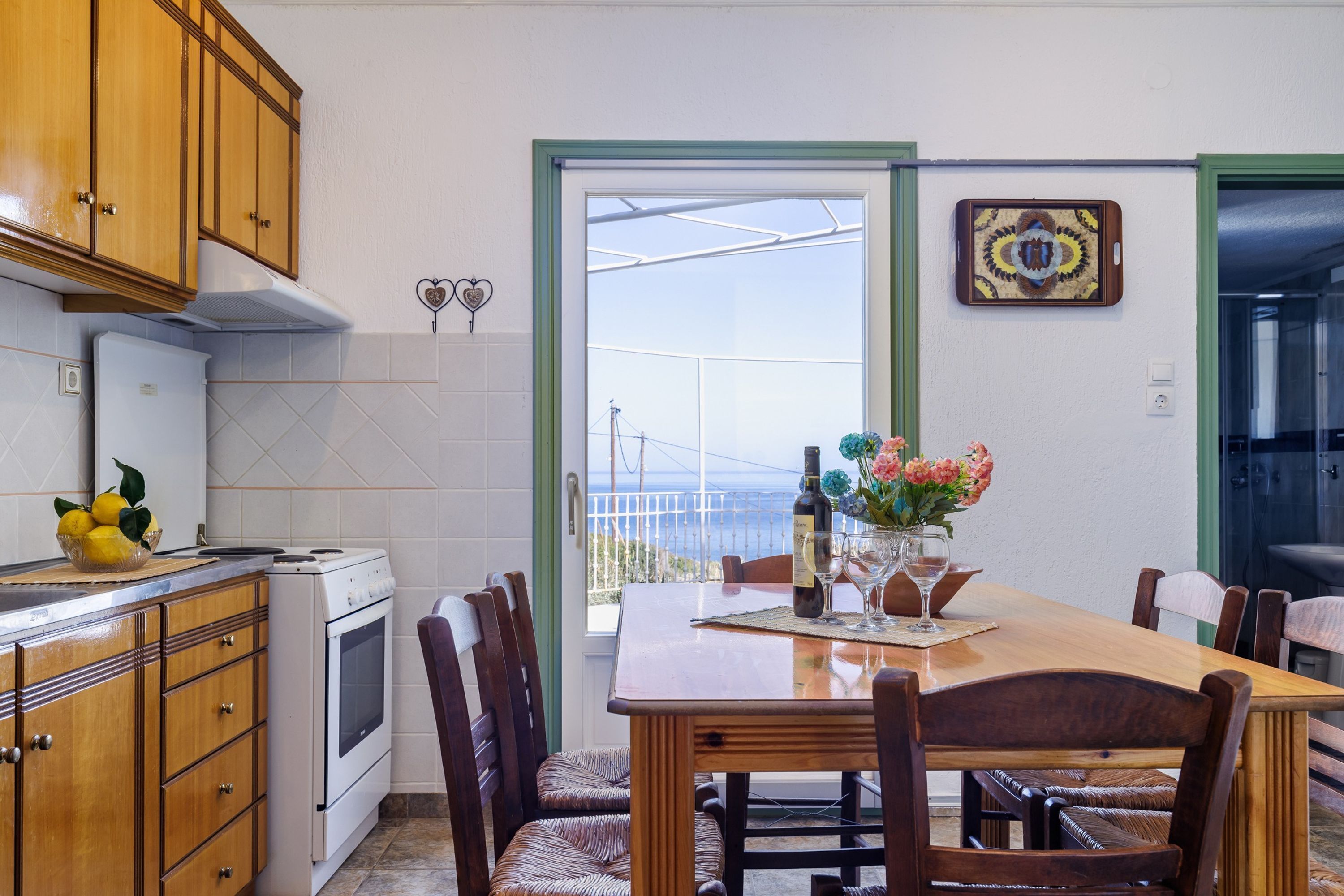 Une cuisine avec des meubles de rangement en bois, une cuisinière blanche et une table à manger avec des chaises.