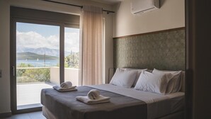 A hotel room with a bed, a view of the sea, and an air conditioning unit. - Two-Bedroom Apartment Sea View (Nikiana)