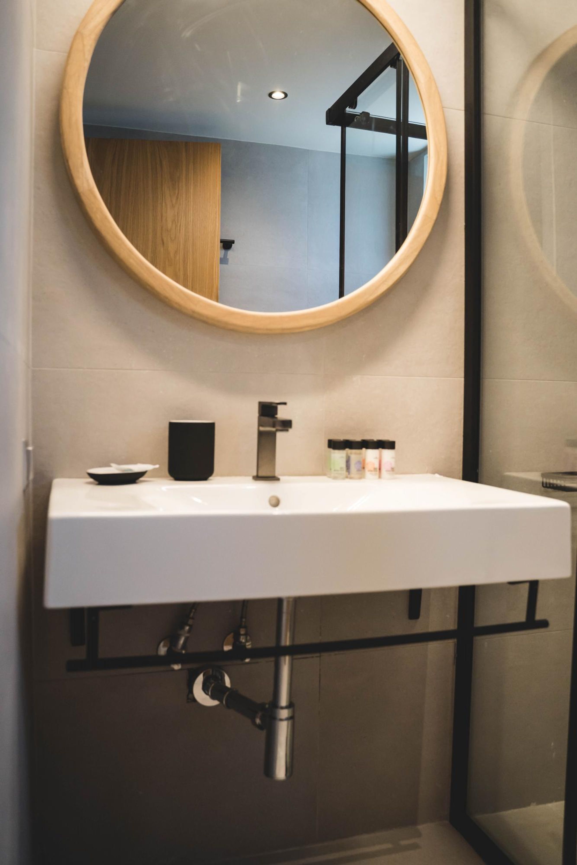 A modern bathroom with a round mirror, white sink, and black faucet.