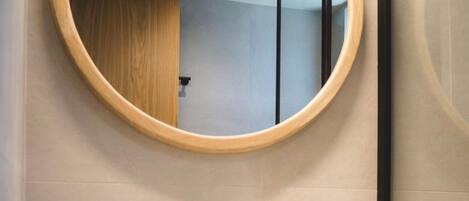 A modern bathroom with a round mirror, white sink, and black faucet.