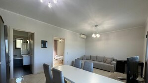 Una cocina moderna con una isla central, un comedor con sillas, un sofá y un televisor.