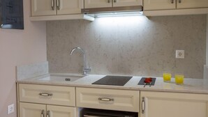 A kitchen with a sink, countertop, and cabinets. There are two glasses of orange juice on the counter. - Tirkouaz Suite - VK Luxury Suites-Private Parking (Nydri)