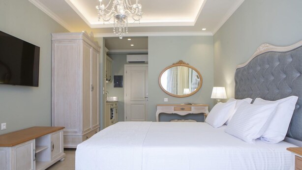 A bedroom with a large bed, a television, a wardrobe, and a mirror. - Tirkouaz Suite - VK Luxury Suites-Private Parking (Nydri)