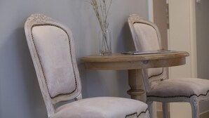 Zwei gepolsterte Sessel mit Zierleisten, ein Holztisch und eine klare Vase mit getrockneten Pflanzen.