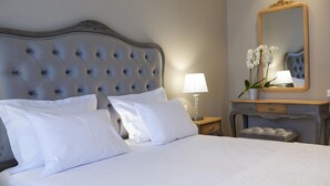 Ein ordentlich bezogenes Bett mit weißen Leinentüchern und einem gepolsterten Kopfteil.