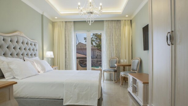 Um quarto espaçoso com uma cama grande, um candelabro, uma área de refeições e vista pela porta de vidro.