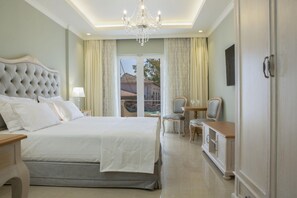 A hotel room with a large bed, a chandelier, a desk, and a view of the outside. - Green Suite - VK Luxury Suites - Private Parking (Nydri)
