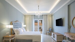 Quarto com cama grande, lustre, televisão e vista para o exterior.