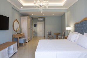 A hotel room with a large bed, a chandelier, a television, a desk, and a chair. - Green Suite - VK Luxury Suites - Private Parking (Nydri)