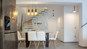 A modern kitchen with a built-in refrigerator, a dining table with chairs, and a staircase leading to another level. - Aloft Luxury - Villa Lefkia with heated pool (Apolpena)