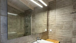 Een moderne badkamer met een grote spiegel, een rechthoekig wastafelmeubel en een houten aanrechtblad.
