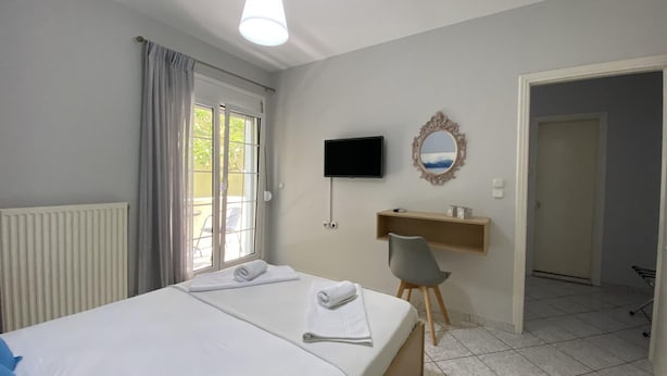 Ein Hotelzimmer mit einem Bett, einem an der Wand montierten Fernseher, einem Spiegel und einem Sessel.