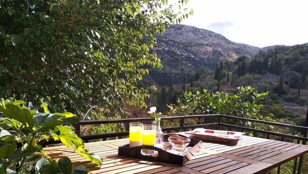 Une table en bois, sur laquelle sont disposés un plateau de nourriture et de boissons, le tout placé devant un paysage montagneux pittoresque.