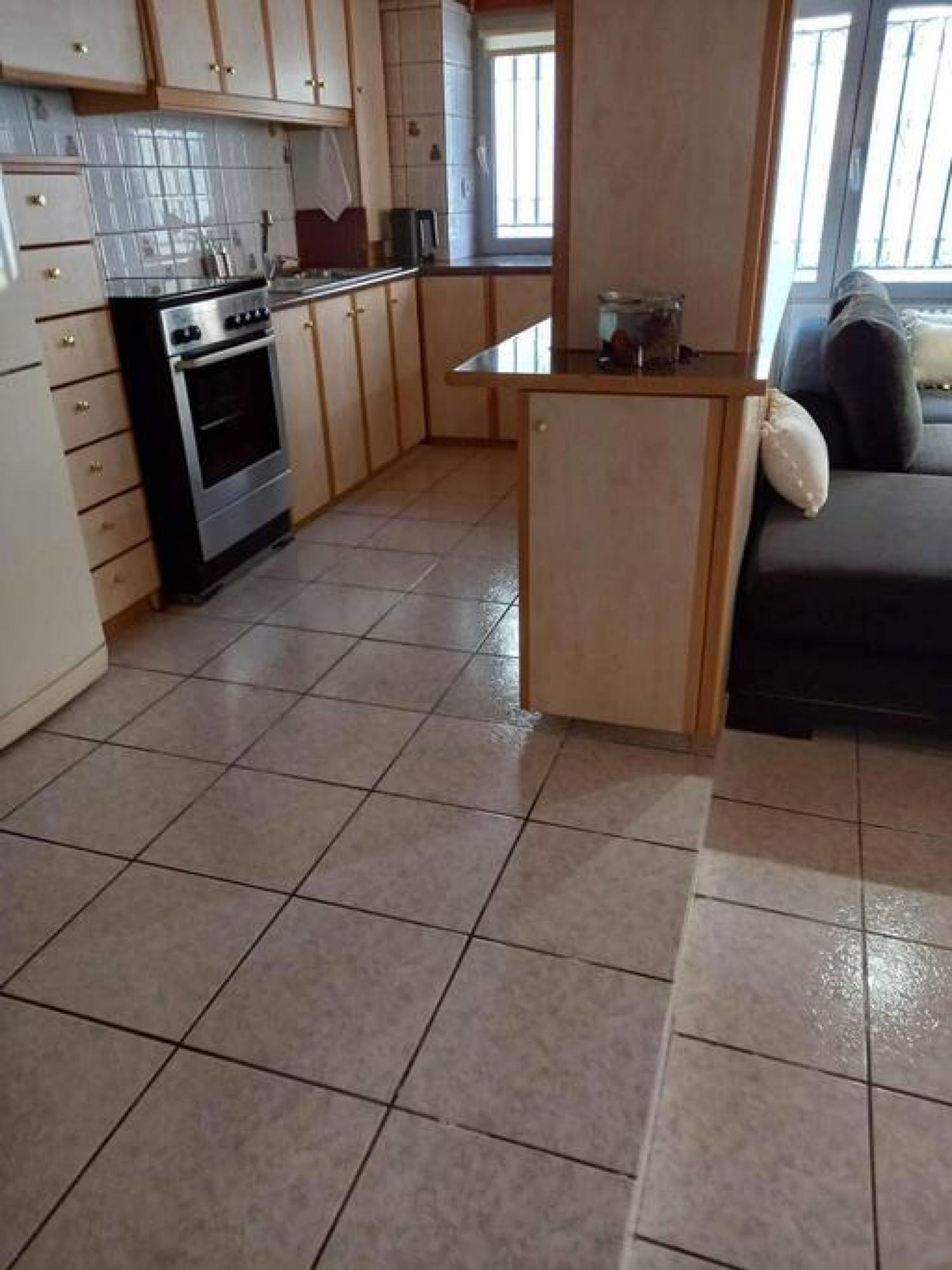 Une cuisine équipée d’un four encastré, d’un petit îlot central et d’une fenêtre.
