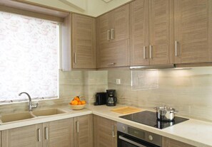 A kitchen with wooden cabinets, a double sink, a coffee maker, and a stove. - Sunny Apartment Lefkada - Lefkada BnB (Kalligoni)