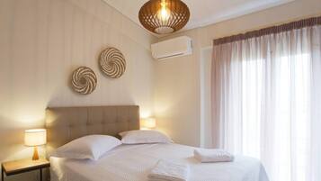 A neatly made bed with white linens, a bedside lamp, and a wall-mounted air conditioner.
