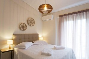 Un lit bien fait, avec du linge de lit blanc, une lampe de chevet et un climatiseur fixé au mur.