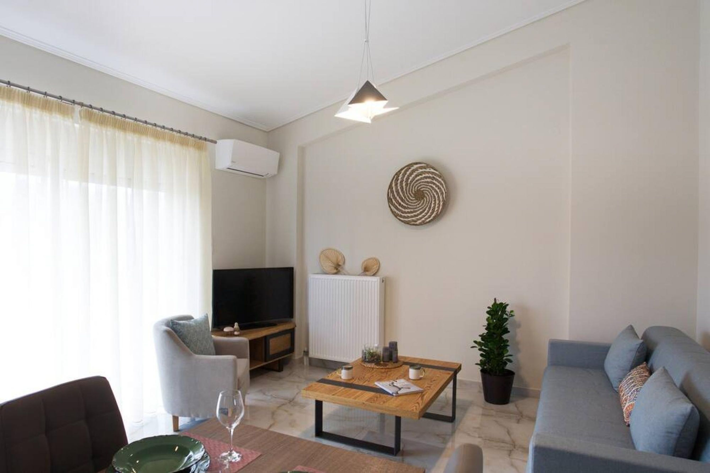 A modern living room with a sofa, a dining table, and a TV.