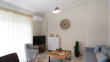 A modern living room with a sofa, a dining table, and a TV.