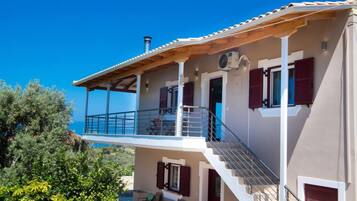 Una casa de dos pisos con balcón, mobiliario exterior y una chimenea.