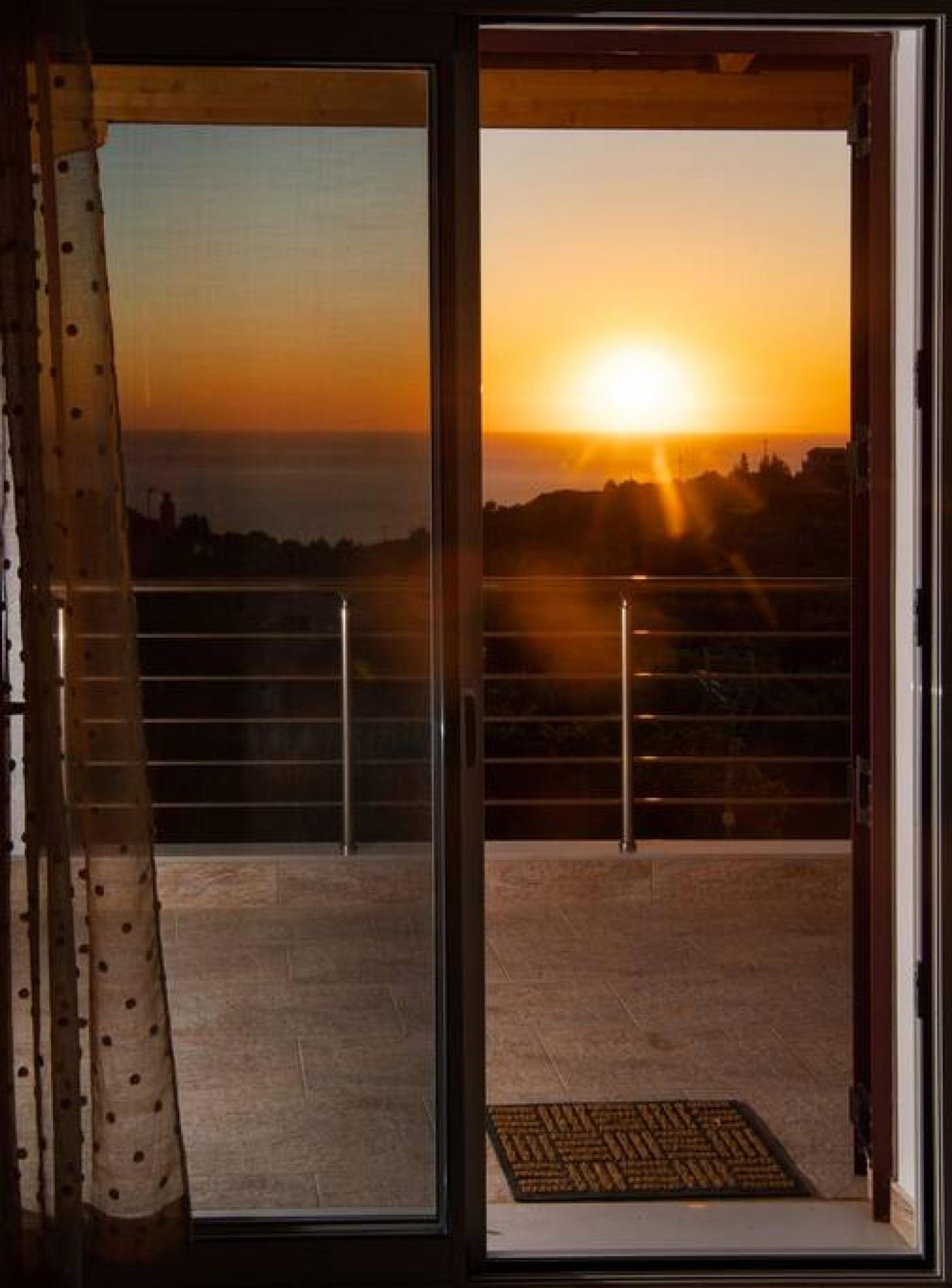 Un balcón con vista al atardecer sobre un paisaje urbano.