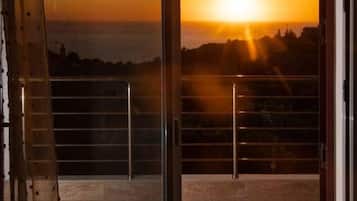 Un balcón con vista al atardecer sobre un paisaje urbano.