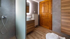 Une salle de bain avec une porte en bois, un lavabo blanc et une douche.
