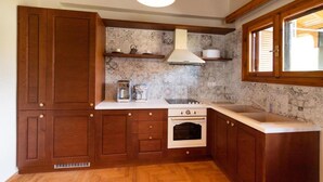 Une cuisine avec des meubles de rangement en bois, une cuisinière, un four et une fenêtre.