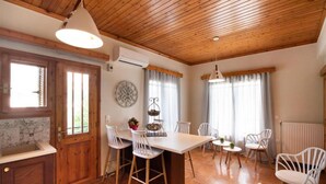 Une cuisine avec des meubles en bois, un grand îlot central doté de tabourets, et un coin repas avec des chaises blanches.