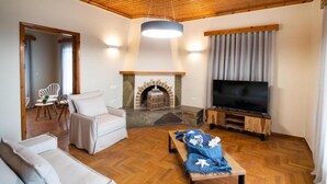 Un salon avec une cheminée, un téléviseur et un plafond en bois.