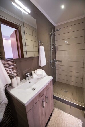 A modern bathroom with a glass-enclosed shower, a vanity with a sink, and a mirror. - NV Pink Suite Nikiana Lefkada — AV Properties (Nikiana)