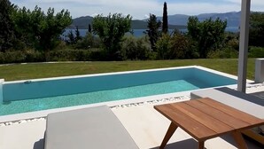 Ein moderner Poolbereich im Freien mit Blick auf das Meer und die Berge.