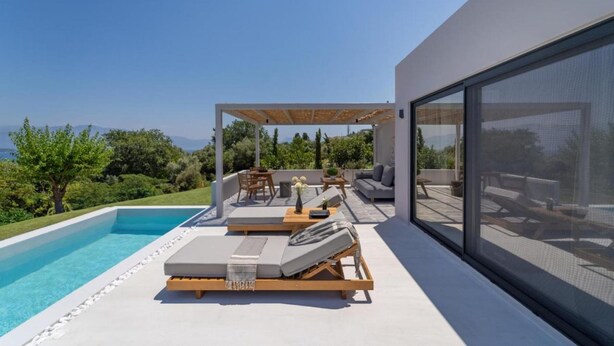 Ein moderner Poolbereich im Freien mit Liegestühlen und einer Pergola, mit Blick auf eine üppige Landschaft.