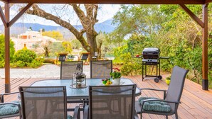 A covered outdoor dining area with a table and chairs, a grill, and a view of a mountainous landscape. - Villa Spyrelia in Dassia (Dassia)