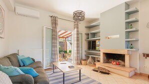 A living room with a sofa, coffee table, fireplace, and shelves. - Villa Spyrelia in Dassia (Dassia)